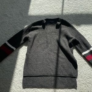 V neck. Grey sweater. Red and white stripes at arms.
